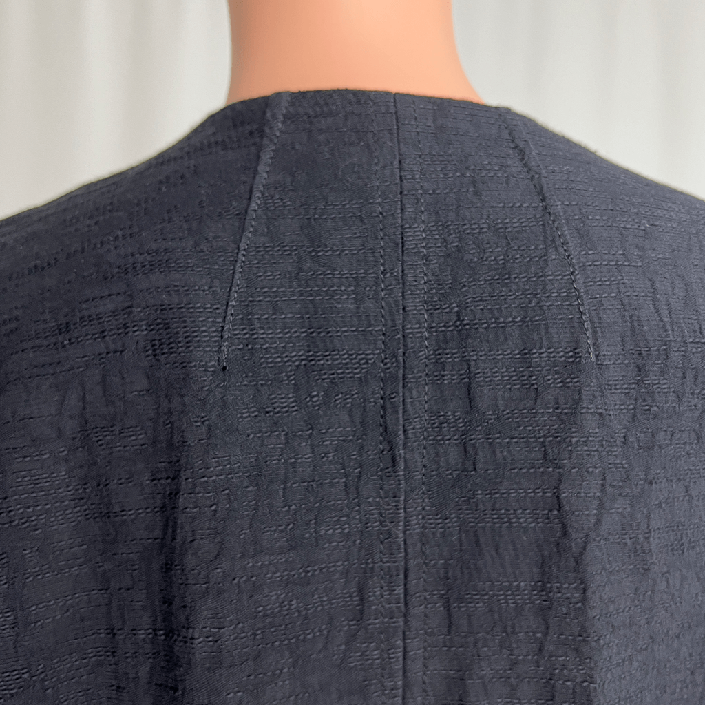 Back collar close up view of the Verge black collarless overcoat