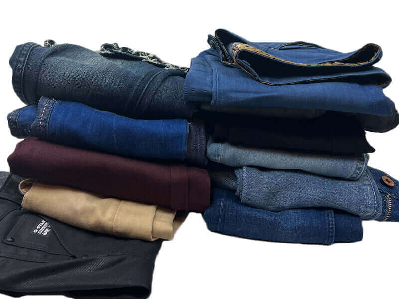 Sleection of jeans piled on top of each other.