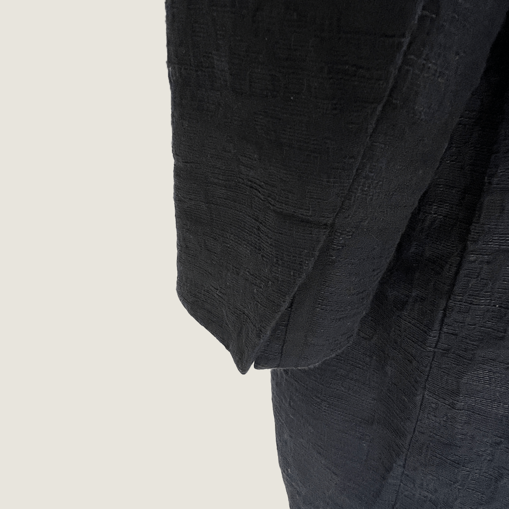 Side sleeve close up view of the Verge black collarless overcoat