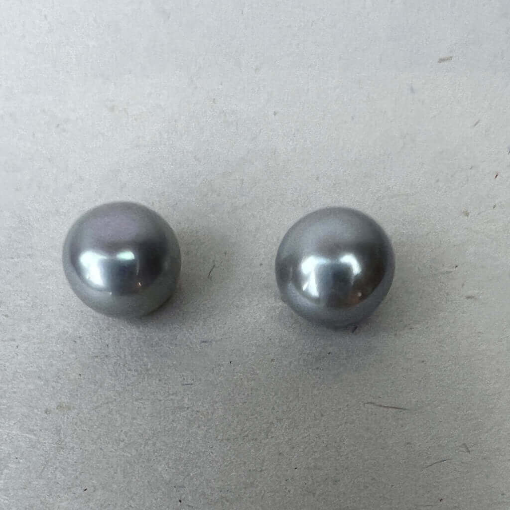 Grey pearl stud earring pair on white background